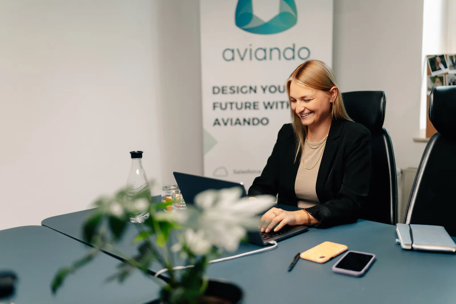 Aviando-Teammitglied lächelt mit Smartphone in der Hand