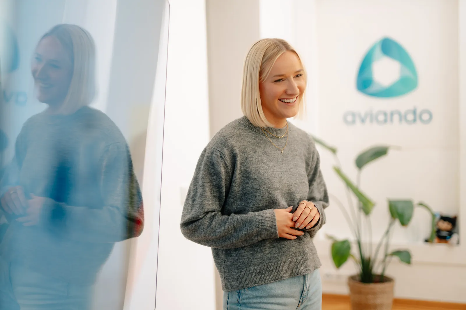 Aviando Beraterin im Gespräch im Büro vor dem Aviando Logo